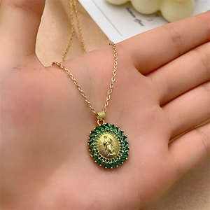 Gold Virgin Mary oval pendant necklace with green zircon border held in hand
