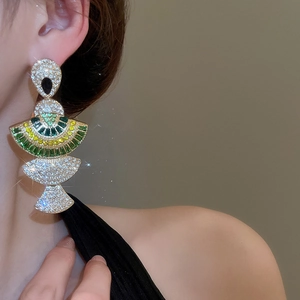 Close-up of gold tiered fan-shaped earrings with green and yellow stones on model