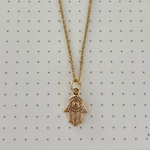 Detailed view of golden Hamsa Hand pendant with intricate engravings and eye pattern