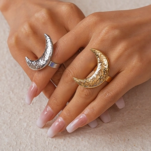Detail of moon-shaped rings with hammered metal texture in gold and silver finish