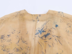 Detail of yellow V-neck floral top showing lightweight chiffon fabric and blue prints