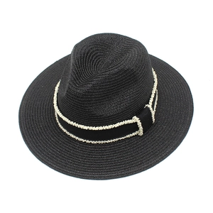 Detail of black straw fedora hat featuring elegant white pearl bead trim on a black ribbon