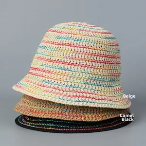 Close-up of three stacked rainbow striped straw sun hats in beige, camel, and black