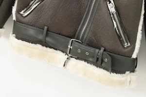 Detail of faux leather jacket hem featuring thick sherpa lining and adjustable metal belt