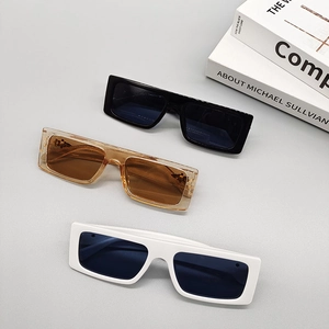 Three pairs of vintage square sunglasses in black, amber, and white colors on a book