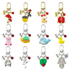 Macro view of twelve assorted enamel keychains featuring dolphin and mushroom charms