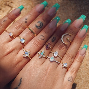 Close-up of gold-plated silver rings with opals and purple crystals on model's hand