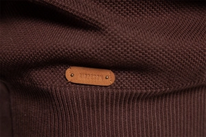 Details der dunkelbraunen Waffelstrick-Textur und Marken-Lederaufnäher am Saum