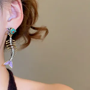 Unique fishbone drop earrings featuring green enamel and pearls on a golden metal base