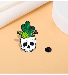 Macro detail of punk enamel cactus skull brooch with green plants and pink flowers