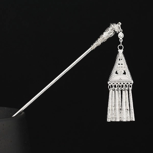 Detailed close-up of ethnic silver hair pin with intricate tassel pendants and engravings