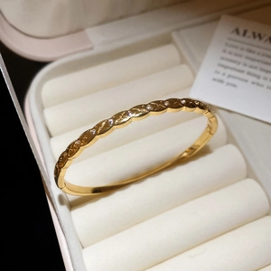 Detail of a gold-plated twisted bangle with inlaid cubic zirconia on a velvet display