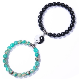 Detail of Yin Yang charms on matte black agate and turquoise stone beaded bracelets