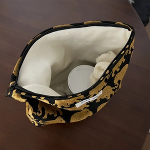Detail of vintage gold elephant jacquard makeup bag showing interior storage and brand label