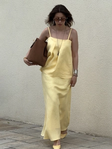 Outdoor street view of a woman wearing a light yellow cotton camisole and maxi skirt set