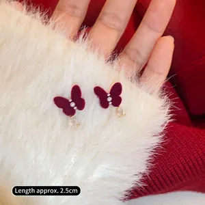 Détail d'une boucle d'oreille nœud floqué bordeaux de 2,5cm avec perles et cristal