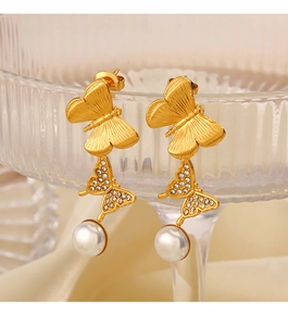 Macro detail of 18K gold-plated butterfly earrings with clear zircons and white pearls