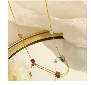 Detail view of 18K gold plated necklace with colorful enamel rectangular charms on mirror