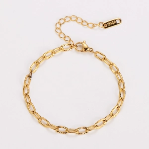 Macro detail of gold-plated embossed link chain bracelet with 18KGP tag and lobster clasp