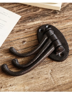 Macro shot of vintage cast iron triple wall hook with textured bronze finish and three hooks