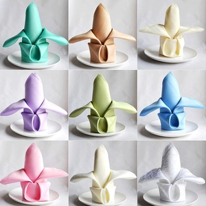 Polyester napkin set in nine assorted colors folded on elegant white dinner plates