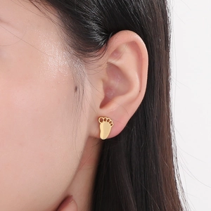 Close-up of a model wearing a gold paw print stud earring in polished stainless steel