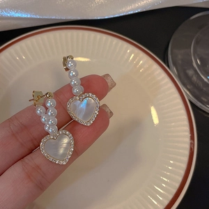 Detailed view of pearl stud earrings with heart-shaped mother of pearl pendants