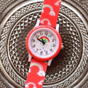 Close-up of red kids watch with rainbow and cloud patterns on silicone strap