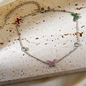 Silver butterfly bracelet with colorful enamel charms on beige stone and silk background