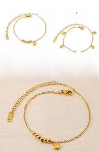 Close-up of gold double-layer heart anklet with pearls and lobster clasp on fabric