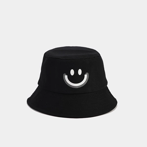 Close-up of black cotton bucket hat featuring a white minimalist smiley face print