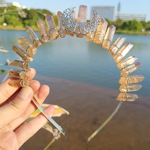Close-up of handmade raw crystal crown with silver hollow moon held in hand outdoors