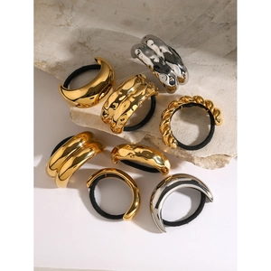 Detail of gold and silver metallic curved hair rings with elastic black bands on stone