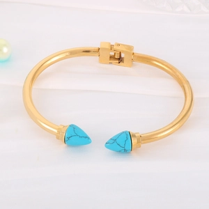 Detail of gold-plated stainless steel cuff featuring blue turquoise pyramid spike studs