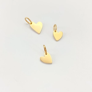 Close-up of three polished gold stainless steel heart pendants for jewelry making