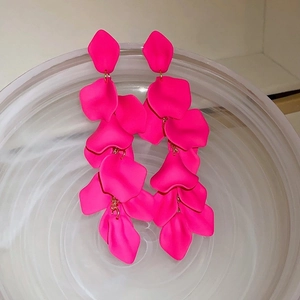 Macro shot of tiered rose pink petal tassel earrings in a textured glass bowl