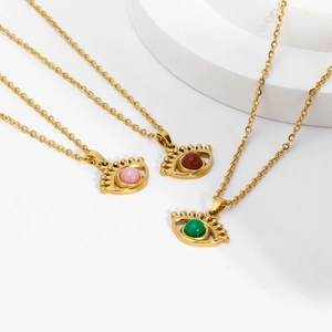Detailed view of evil eye necklaces with pink, red, and green pendants on white stone
