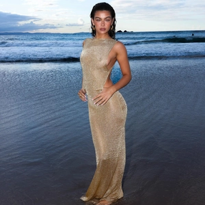 Detail of gold glitter knit maxi dress with side split shown at beach sunset