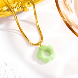 Detailed close-up of golden snake chain and light green acrylic flower pendant with texture