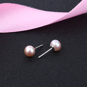 Macro shot of pink freshwater pearl earrings with silver posts on elegant leather