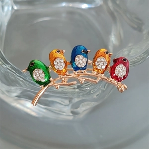 Detail of colorful enamel birds brooch with sparkling crystals on a golden branch
