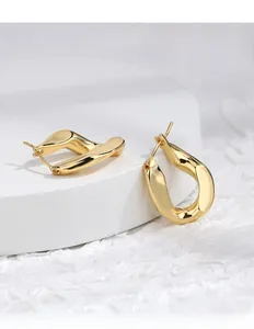 Close-up of twisted golden egg-shaped hoop earrings with a sleek minimalist metallic finish
