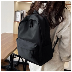 Detail of minimalist black nylon backpack featuring large capacity and sleek zipper pockets