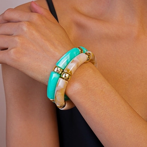 Détail d'un bracelet de perles aux motifs de marbre vert et beige et espaceurs dorés
