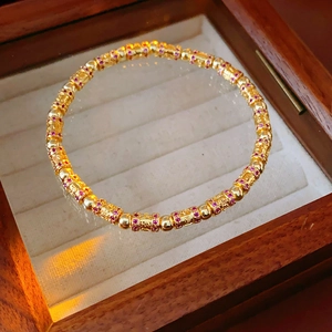 Close-up of 18k gold plated bracelet with zircon cylinders and purple gemstones