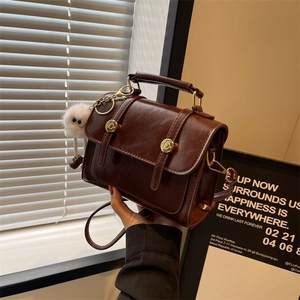 Vintage dark brown crossbody bag with gold hardware and a white plush keychain