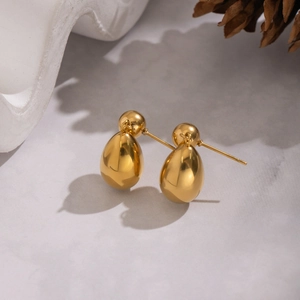 Minimalist golden teardrop earrings in polished stainless steel on a marble background