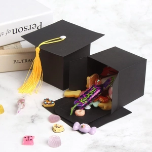 European graduation cap candy box with yellow tassel on white marble surface