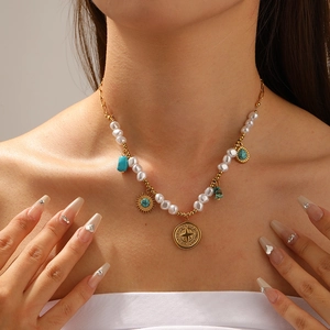 Detail of gold necklace featuring white pearls, turquoise stones and star medallion