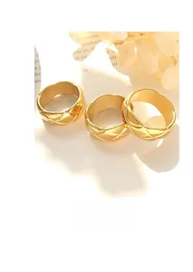 Macro detail of three gold-plated titanium steel rings featuring quilted pattern engraving